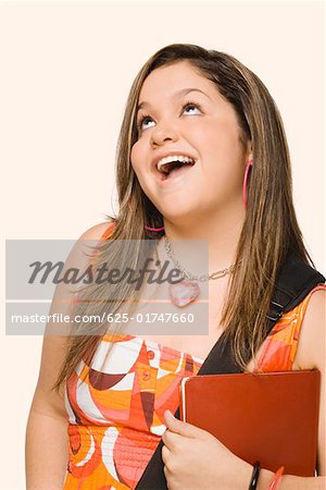 Gros plan d'une jeune femme tenant un journal et souriant