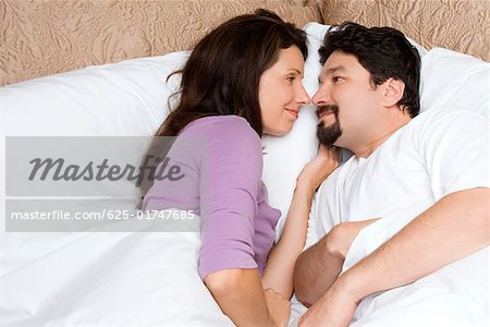 High angle view of a mid adult couple lying on the bed and looking at each other