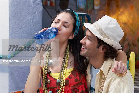 Nahaufnahme einer jungen Frau mit einem jungen Mann und Wasser aus einer Flasche Wasser sitzen