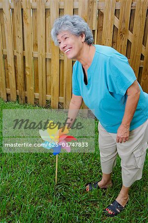 Side profile of a senior woman fixing a pinwheel in a lawn and smiling