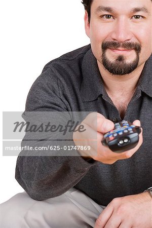 Portrait d'un homme adult moyen tenant une télécommande et ricaner