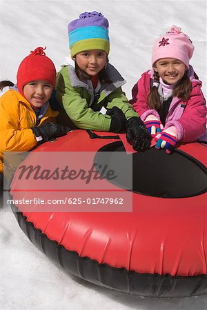 Portrait of three girls sitting near an inner tube