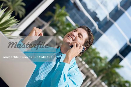 Homme d'affaires parlant sur un téléphone mobile et excité à la recherche