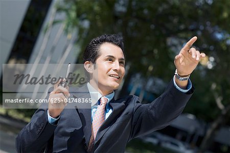 Businessman holding a mobile phone and pointing upward