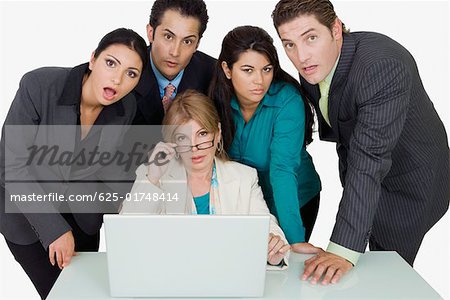 Portrait of a businesswoman adjusting her eyeglasses and two businesswomen with two businessmen standing beside her