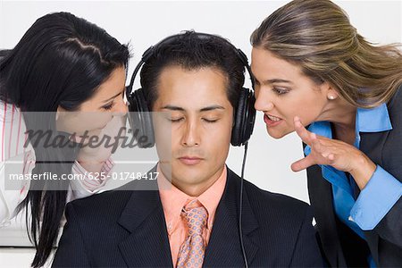 Gros plan d'un homme d'affaires, écouter de la musique tandis que deux femmes d'affaires le tracasse