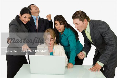 Geschäftsfrau mit vier Geschäftsleute neben ihr auf einem Laptop arbeiten