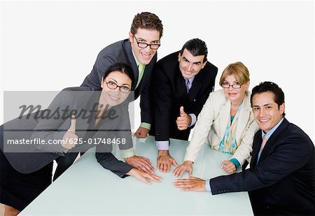 Portrait of two businesswomen and three businessmen placing their hands on the table