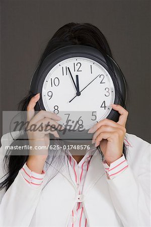 Gros plan d'une femme tenant une horloge en face de son visage