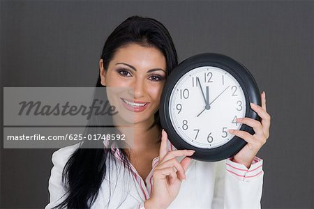 Close-up of a businesswoman holding a clock and smiling