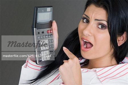 Portrait of a businesswoman pointing at a calculator