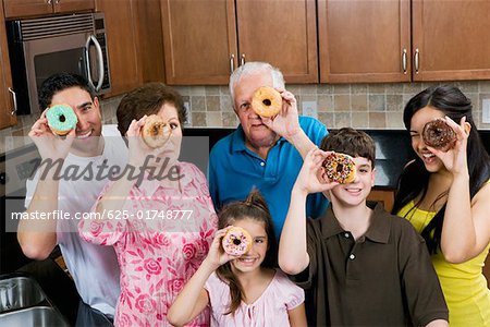 Three generation family looking through donuts