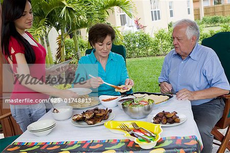 Young woman serving food to her grandparents