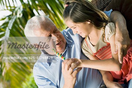 Jeune fille assise avec son grand-père et tenant un bonbon