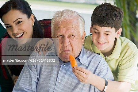 Teenage boy feeding a yellow bell pepper to his grandfather