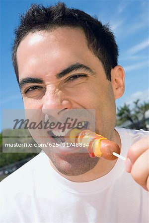 Portrait d'un homme adult mid manger une saucisse