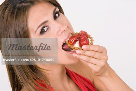 Portrait d'une jeune femme mangeant une tarte aux fraise