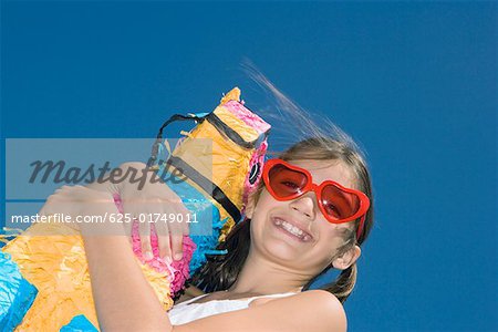 Low angle view of a girl holding a rocking horse and smiling