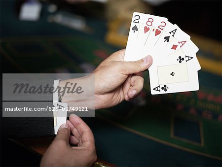 Close-up of a person's hand holding playing cards and hiding an ace in his cuff
