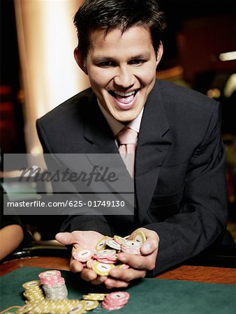 Nahaufnahme eines jungen Mannes mit Handvoll Chips in einem Casino-Glücksspiel jubeln