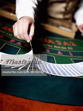Mitte Schnittansicht des Arbeitnehmers Kasino Hand Umgang mit Spielkarten auf einem Spieltisch