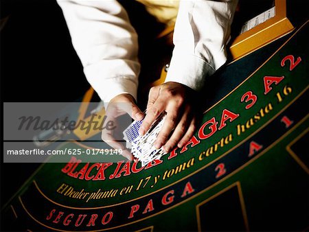 Mid section view of a casino worker's hand shuffling playing cards on a gambling table