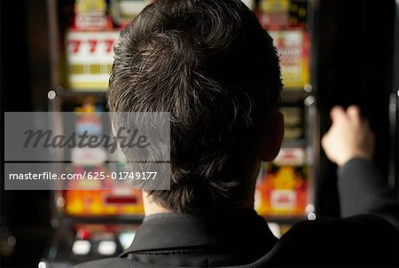 Rear view of a mid adult man playing on a slot machine