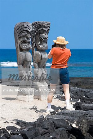 Rückansicht einer Frau Fotografieren des Tikies an der Küste Puuhonua O Honaunau National Historical Park, Kona Coast, Big