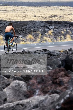 Rückansicht eines Mannes mit dem Fahrrad auf der Straße, Kona Coast, Inseln Big Island, Hawaii, USA