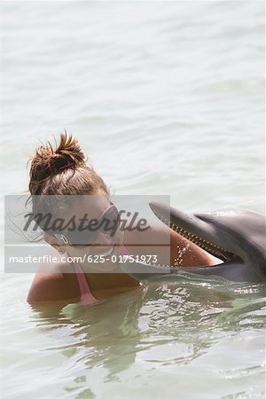 Teenager-Mädchen spielen mit einem Delphin, Roatan, Bay Islands, Honduras