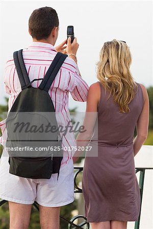 Rear view of a mid adult couple taking photographs with a mobile phone, Capri, campania, Italy