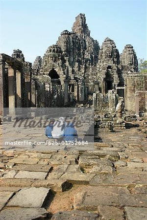 Rear view of three tourists at a temple, Angkor Wat, Siem Reap, Cambodia