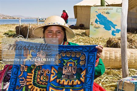 Portrait of a young woman showing a decorated blanket, Peru