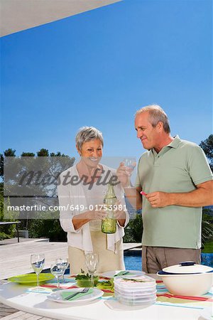 Man and woman drinking by poolside.
