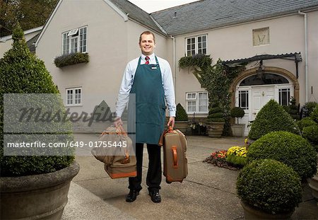 Homme transportant des bagages à l'extérieur de l'hôtel.