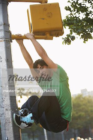 Teenaged Boy Climbing on Traffic Light