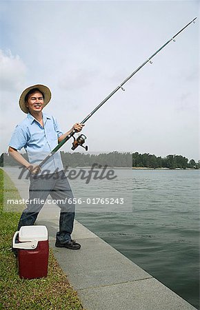 Man fishing with fishing pole, looking at camera, smiling