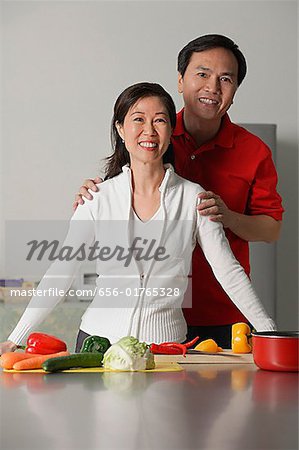 Mature couple in kitchen, smiling at camera