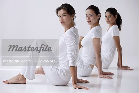 trois femmes assises sur le sol, vue de côté, regardant la caméra