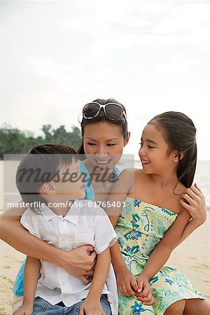 Mother, daughter and son sitting on beach together