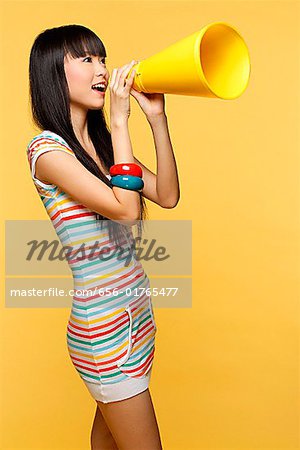 Young woman shouting through yellow megaphone