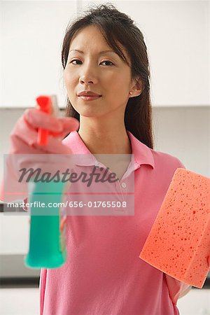 Woman cleaning with cleaning spray and sponge, spraying at camera