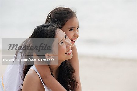 Mutter und Tochter am Strand, Tochter, die Mutter von hinten umarmt