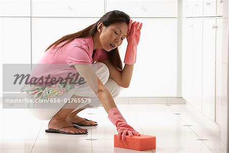 Fatigué femme nettoyer le plancher de la cuisine avec une grosse
