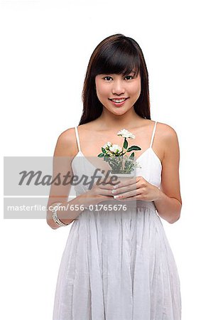 Jeune femme vêtue d'une robe blanche et de trouer la petite plante