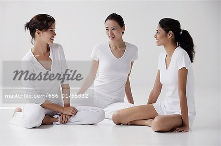 three women of mixed race sitting on floor talking