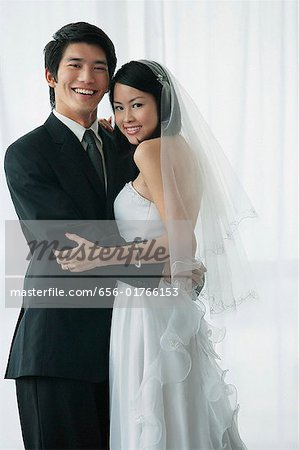 A newlywed couple hug and smile at the camera