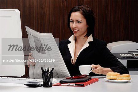 Une femme prend une pause au travail et lit le journal