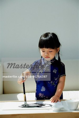 Une petite fille en bleu cheongsam soie écriture de calligraphie chinoise