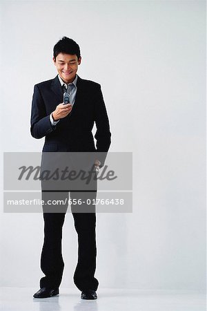 Un homme vêtu d'un costume sourit comme il compose sur son téléphone portable